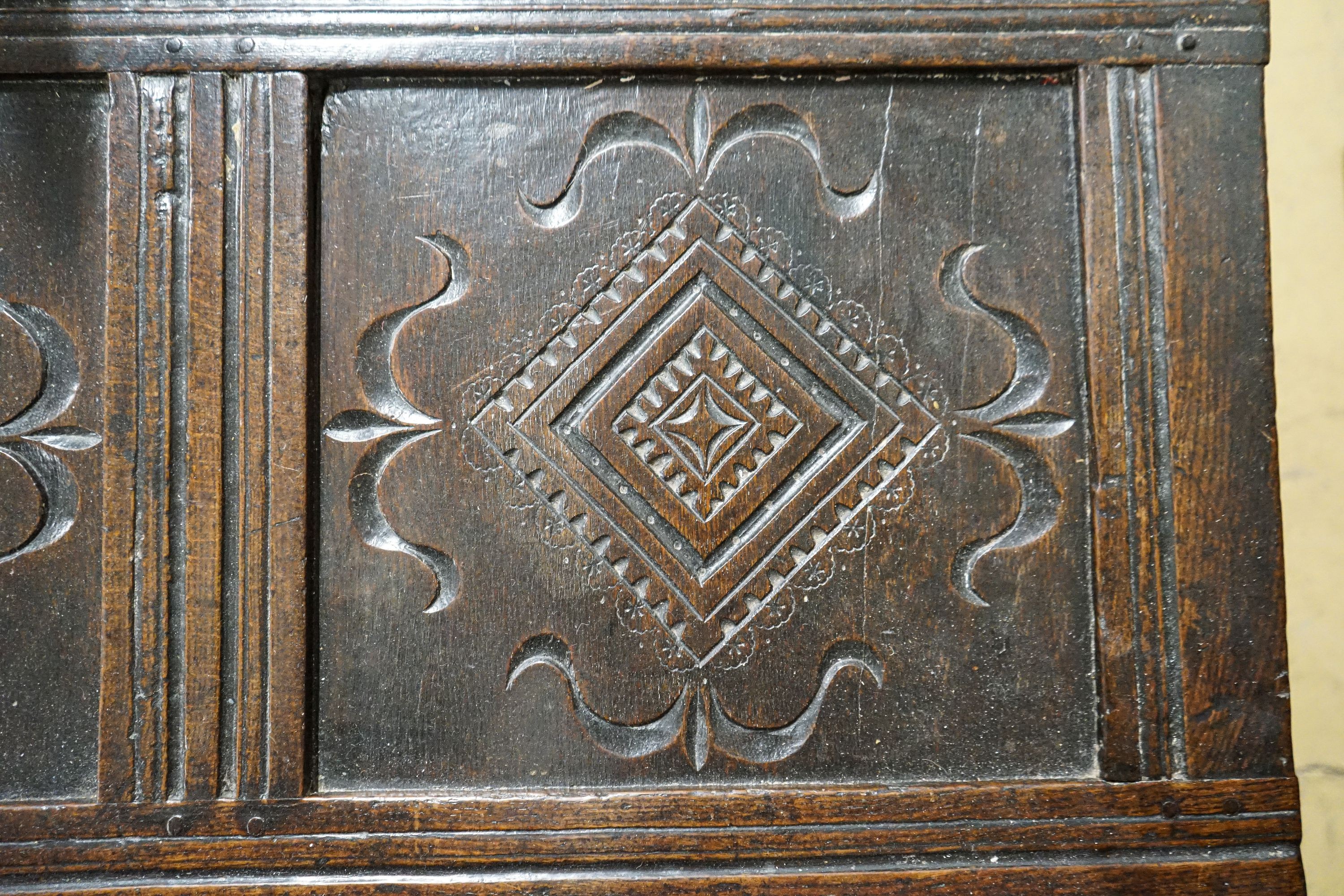A late 17th/early 18th century carved and panelled oak coffer with hinged lid, width 136cm, depth 51cm, height 58cm